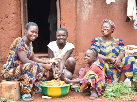 sponsored children with their mother sit outside their home in the DRC