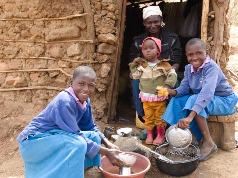 Anastacia and her daughters wash dishes after eating a small ration of maize.