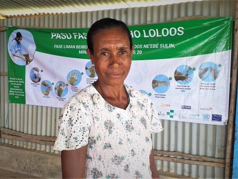 Amelia is standing in front of prevention awareness banner after meeting World Vision. Image: Natalino Tilman / World Vision