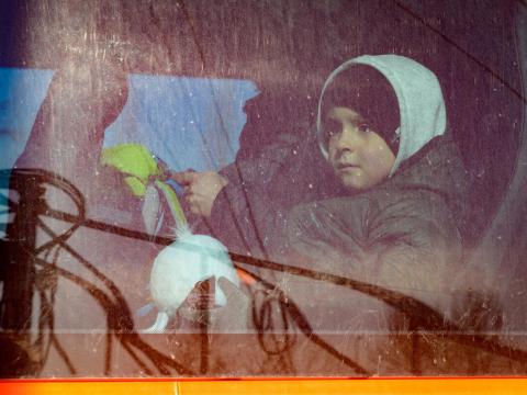 Young child sits on a bus after leaving Ukraine