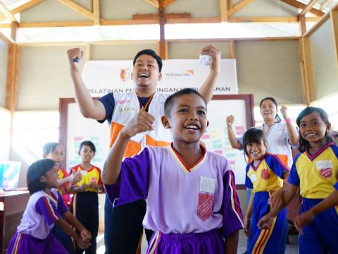 World Vision staff cheer with children 