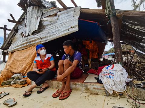 World Vision staff member sits with survivor in the Philippines following the typhon 