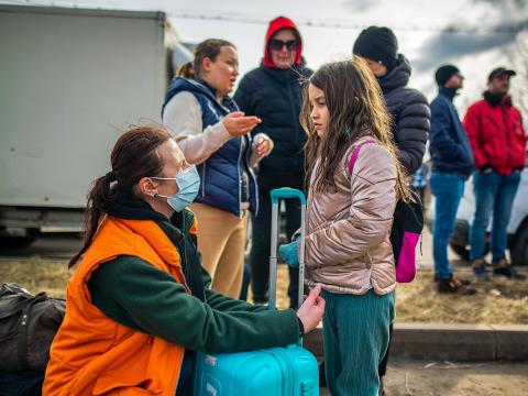 World Visions staff speak with a young girl on the Romania border