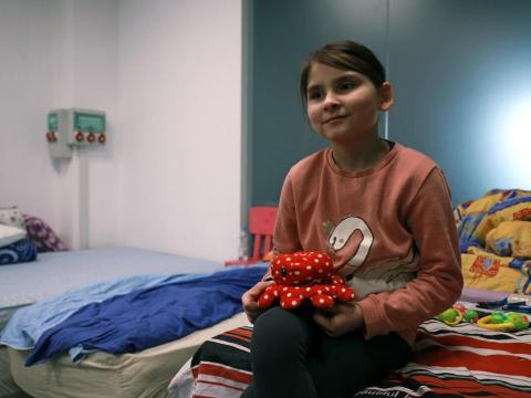 9-year-old Diana sits on a bed in a refugee transitional housing supported by World Vision in romania