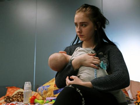 Lisa and her baby seated on a bed