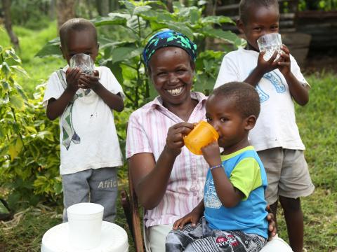 Lily, a mother of 11, poses with some of her children as they enjoy clean water. She and her neigbours can now enjoy purified water following intervention by World Vision and P&G. 
