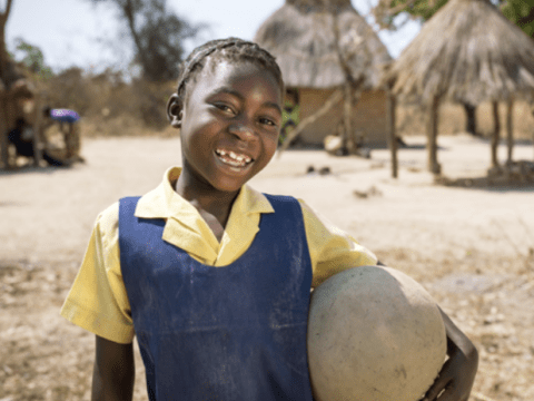 girl standing outside holding a ball