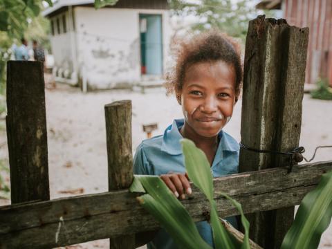 child stands behind fence