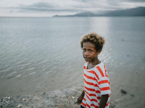 boy stands in front of a body of water