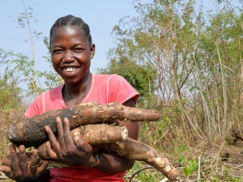 young girl holds armful of logs