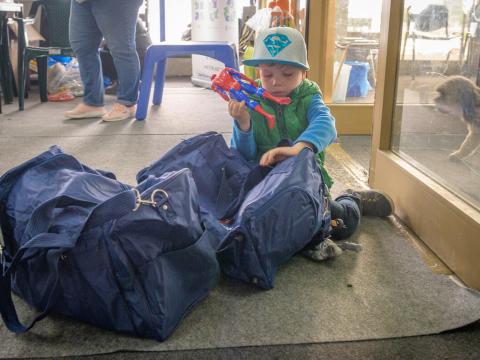 Refugee child from Ukraine sits by their family's bags