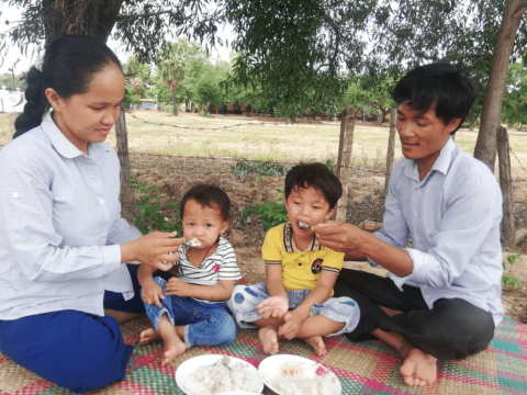 Women sit on the ground feeding their children