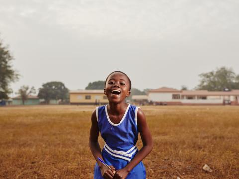 young girl stands in a field smiling and laughing