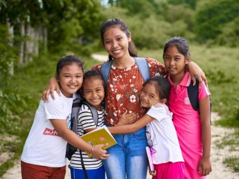 a group of girls hug as they look at the camera