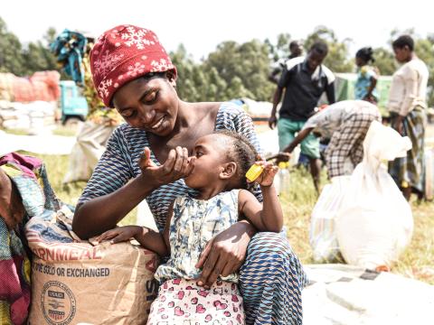 Une femme donnant à manger à son enfant dans un site de distribution des vivres