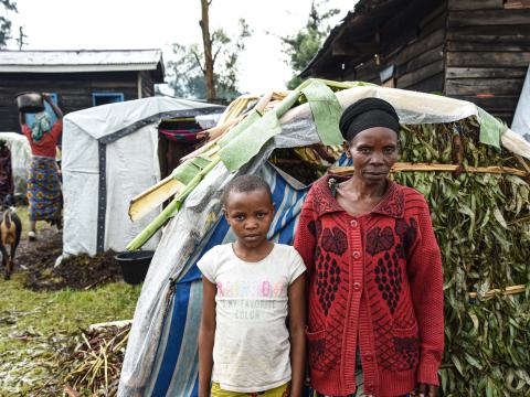 Tumaini and her mother in front of their shelter