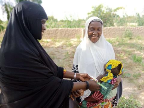 Halima weighing a child with the perimeter brachial 