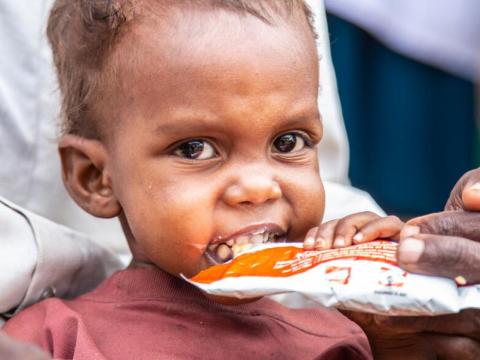 child eats from a ready-to-eat packets to help address malnutrition