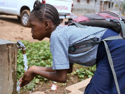 A school pupil enjoying water from one of the World Vision installed taps in her school compound 