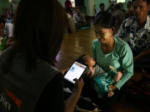 World Vision staff using a cellphone to monitor aid given out to recipients