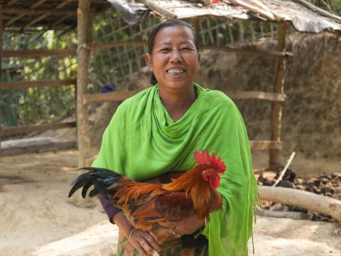 One figure, a woman holding a chicken and smiling