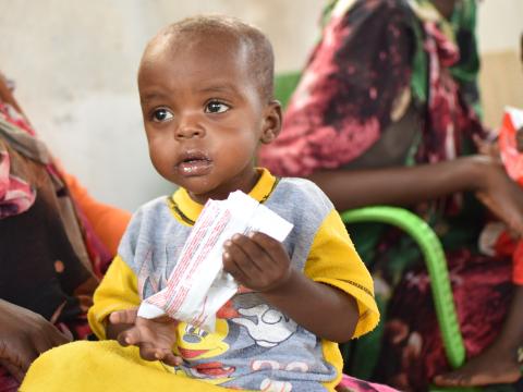 A child holds a packet of ready to eat therapeutic food used to treat malnutrition at a World Vision supported clinic in Sudan