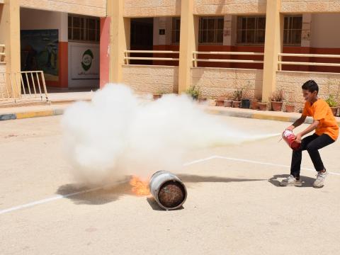 Palestinian Child Learning to use a fire extinguisher during a DRR activity in school