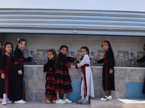 Group of Palestinian students around the new water taps