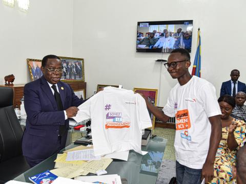 A child giving a t-shirt to the DRC senate president as a symbol to enroll him in the change maker movement