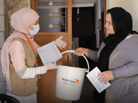 World Vision staff handing aid to a woman in Lebanon