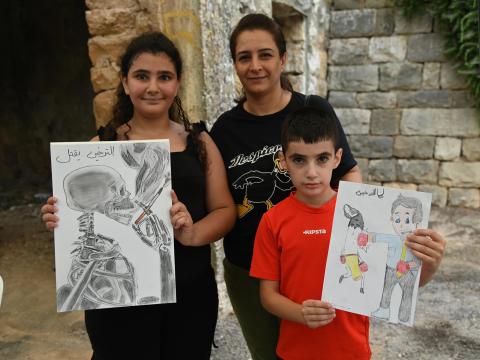 two paintings held by two children illustrating the hazards associated with smoking tobacco.