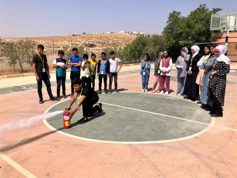 Palestinian Child Learning to use a fire extinguisher during a DRR activity in school