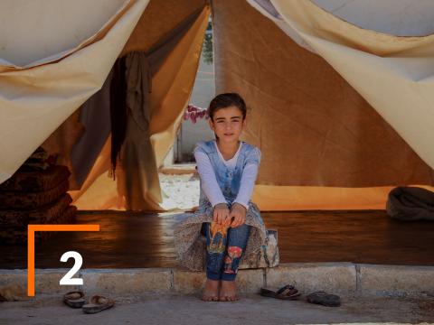 A Syrian girl displaced by war sitting in a tent