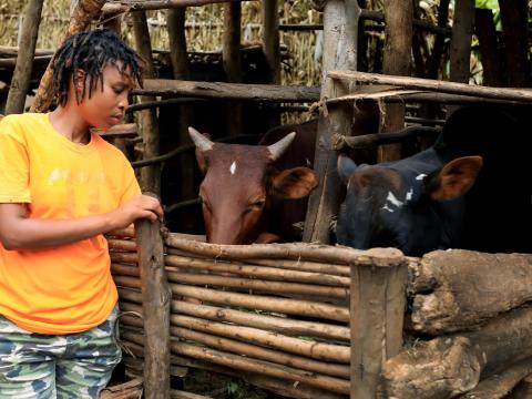 Ange feeding her livestock that she acquired through PAC Project.