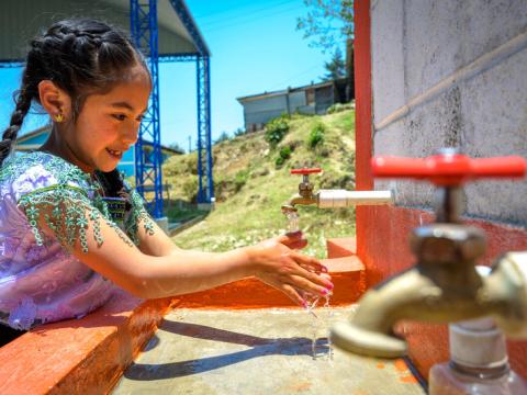 Girl washes hands at tap