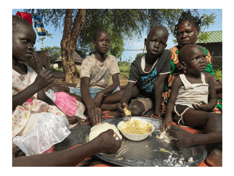 Eight year old, Mandela eats food with his siblings in Juba, South Sudan.