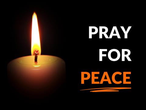 Pray for Peace burning candle against a dark background