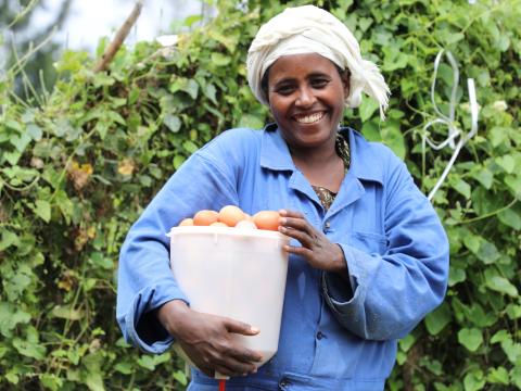 Jemila smiling and holding a bucket of eggs