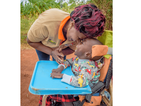 Annastacia Mutunga, the child well-being facilitator in Mwala AP, greets and plays with Dennis during a home visit. Dennis' face lit up when he saw her.