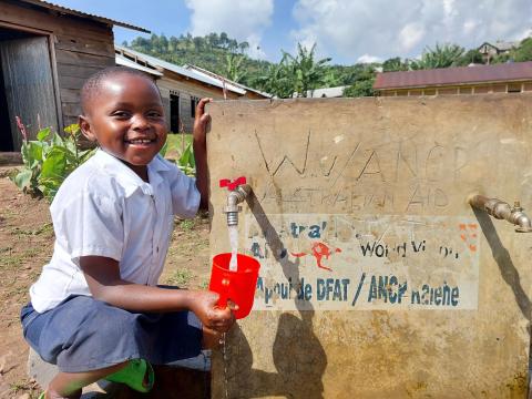 Huguette puisant de l'eau au point d'eau de son école