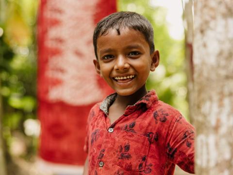 Young boy from India wearing red shirt and smiling