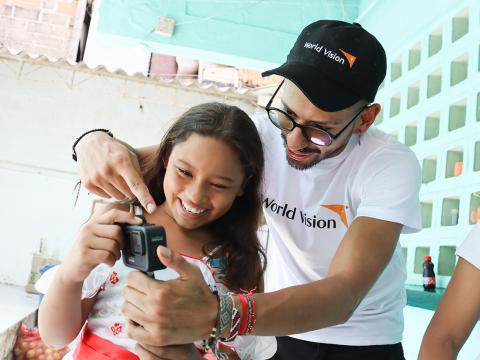 World Vision staff member lets child look at camera