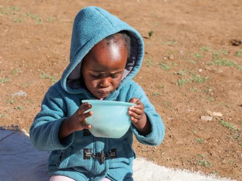 Mpho, 5 years enjoying her nutritious porridge prepared at the Nutrition Club