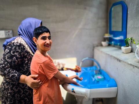Suha* helping Harith with washing his hand and face. Dastan Sabah © World Vision 2024.