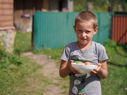 A little boy holding a plate with eggs in it