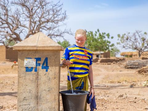 Kadia, collecting water at the public fountain in Djekouma, Mali