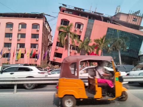 Orange vehicle drives past building damaged in Myanmar