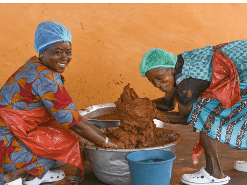 Madam Grace and colleague preparing shea solution to extract butter.