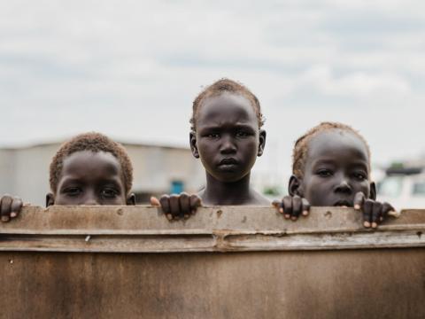 Children displaced by conflict in Sudan look over wall