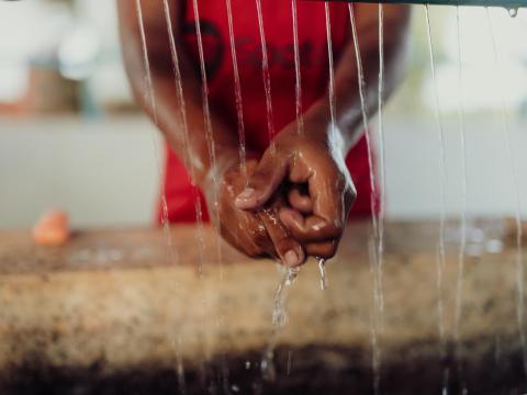 A child is washing her hands at a handwashing station.
